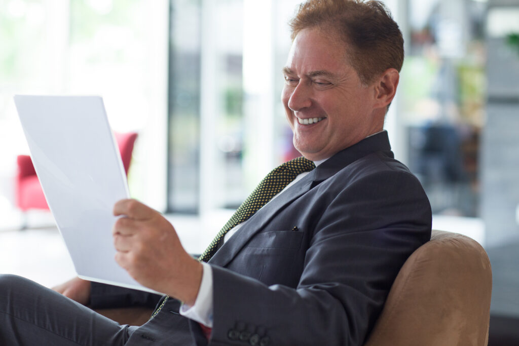 positive businessman reading document on couch